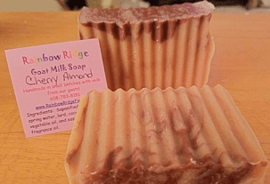 Two bars of Cherry Almond goat milk soap next to a pink informational label.