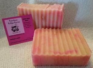 Two bars of pink and white striped soap next to a business card for Rainbow Ridge Farms.