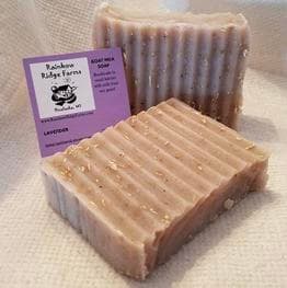 Two bars of lavender goat milk soap beside a business card from Rainbow Ridge Farms.