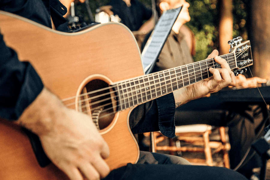 A person's hand strums an acoustic guitar.