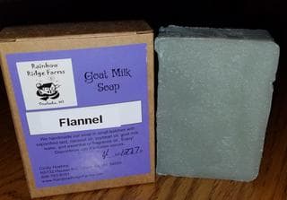 A bar of goat milk soap labeled "Flannel" beside its cardboard packaging.